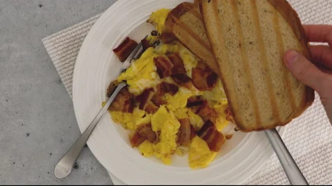 Scrambled eggs fried with bacon and cheese, and served with bread toast Stock Footage 238789876