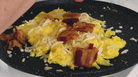 Scrambled eggs fried with cheese and bacon. English breakfast recipe Video stock 225917837