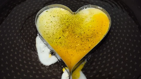 Scrambled eggs in a frying pan are a heart shape. Bright yellow yolk in the f Stock Footage 89034216