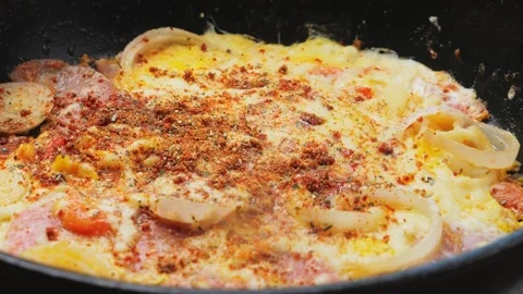 Scrambled eggs in a frying pan with ham and tomatoes and cheese with spices.. Stock Footage 278611148