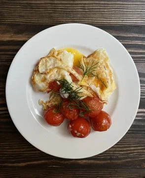 Scrambled eggs at home with cherry tomatoes on a dark wooden background Stock Photos