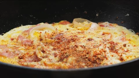 Scrambled eggs in a large frying pan with ham and tomatoes and cheese with .. Stock Footage 277416885