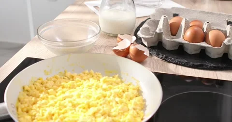Scrambled eggs with milk into a frying pan. Making an omelet. Close up. Stock Footage 243772907