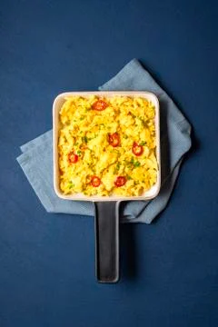 Scrambled eggs pan close-up on blue table. Breakfast food Stock Photos