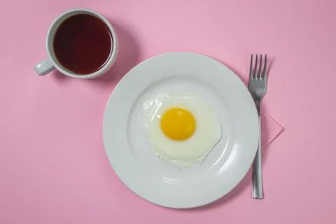 Scrambled eggs on a pink background. Fried eggs on a white plate. Stock Photos