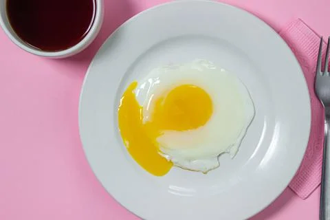 Scrambled eggs on a pink background. Fried eggs on a white plate. Stock Photos