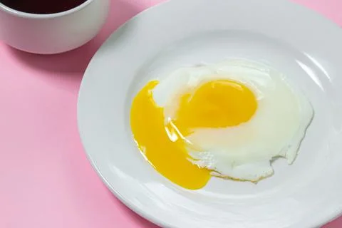 Scrambled eggs on a pink background. Fried eggs on a white plate. Stock Photos