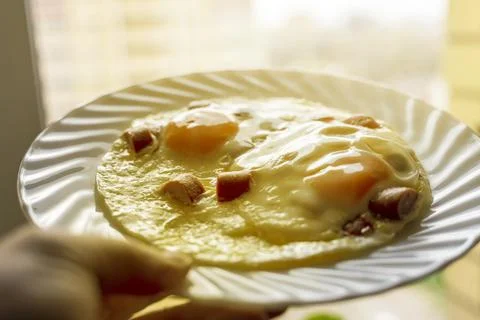 Scrambled eggs with sausages on the background of the window with a plate in Stock Photos
