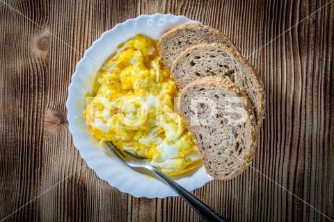 Scrambled eggs served with bread. Stock Photos