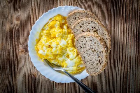 Scrambled eggs served with bread. Stock Photos