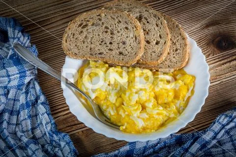 Scrambled eggs served with bread. Stock Photos