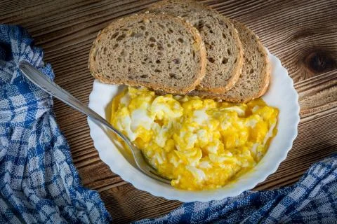Scrambled eggs served with bread. Stock Photos