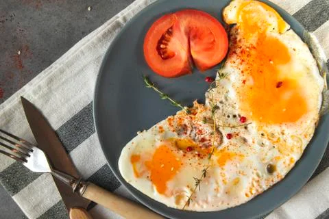 Scrambled eggs with thyme and pepper and spices, a piece of fresh tomato on a Stock Photos