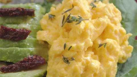 Scrambled eggs with thyme served on a plate with leafy greens Stock Footage 348260364