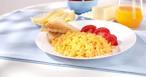 Scrambled eggs with toasts and tomato. breakfast on a white plate. Stock Footage 241755411