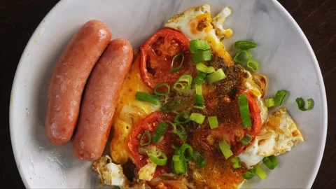 Scrambled eggs with tomatoes and fried sausages sprinkled with green onions.. 库存影片 289882919