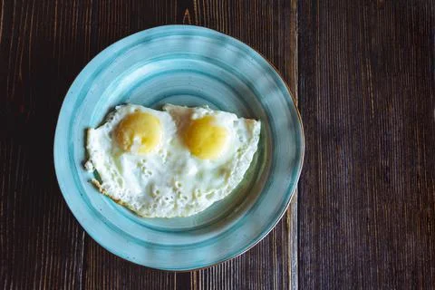 Scrambled eggs on a turquoise plate on a rough dark wooden table, breakfast i Stock-Fotos