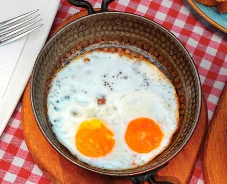Scrambled eggs from two eggs in a frying pan, wooden stand and checkered Foto stock