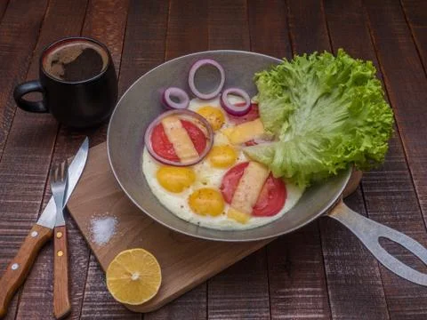 Scrambled eggs with vegetables and cheese on a wooden table. Stock Photos