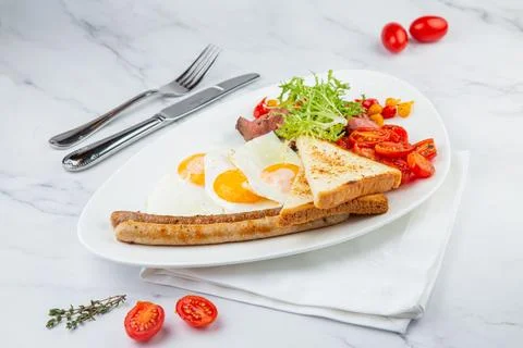 Scrambled eggs with vegetables, cherry tomatoes, bread, herbs and sausages on a Stock Photos