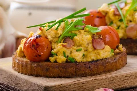 Scrambled eggs witch bacon, herbs and tomato Foto stock