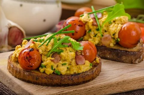 Scrambled eggs witch bacon herbs and tomato Stock Photos