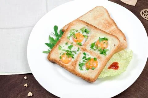 Scrambled fried eggs and bread in the shape of a heart with hot toasts and salad Stock Photos