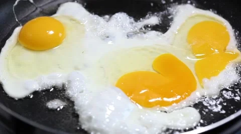 Scrambled from three raw eggs fried in a pan, close-up Stock Footage 65118511