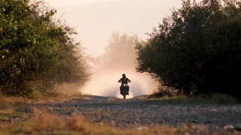 Scrambler Motorcycle Riding Toward Camera on Dusty Road at Sunset Video stock 323556896