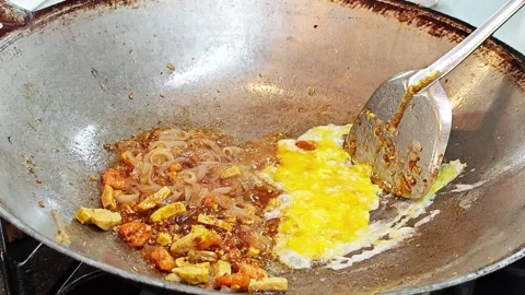 Scrambling egg next to Pad Thai rice noodles in a wok close up. 스톡 동영상 339078411