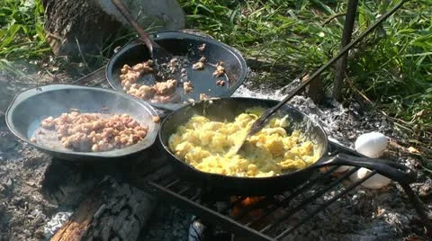 Scrambling eggs over campfire Stock Footage 11197570