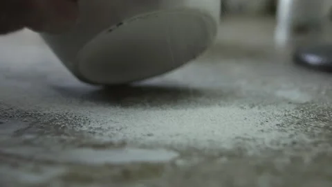 The scraper grinds the surface of the jug. A crumb of clay falls on the tabl Video stock 130526492