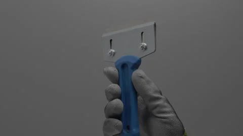Scraper for removing old paint in hand on a gray background. Stock Footage 265597552