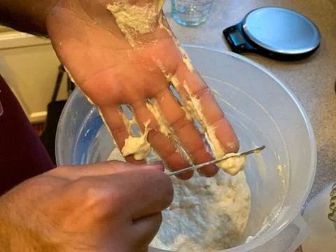 Scraping Bread Dough off of Hands While Baking Bread at Home During Covid19 Stock Photos