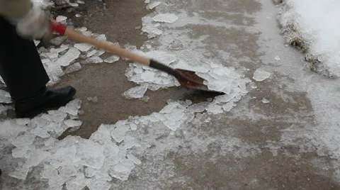 Scraping ice from concrete sidewalk using a spade after freezing rain Stock Footage 33736073