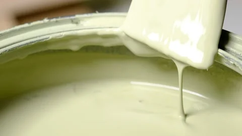 Scraping paint off both sides of a paintbrush on the side of a paint can Stock Footage 138956456