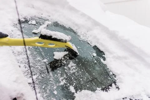 Scraping snow off a car windshield Stock Photos