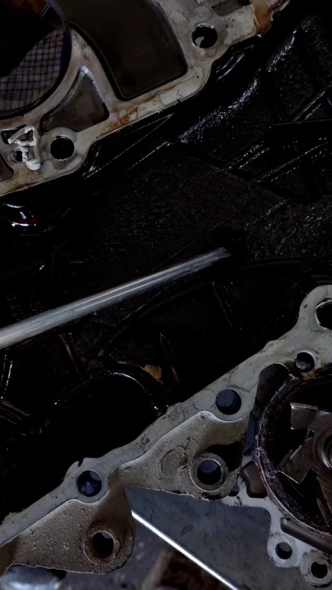 Scraping thick black oil sludge from a metal engine part 스톡 동영상 334321642