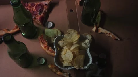 Scraps of food and empty beer bottles on the table in living room, jumble Video stock 246739984