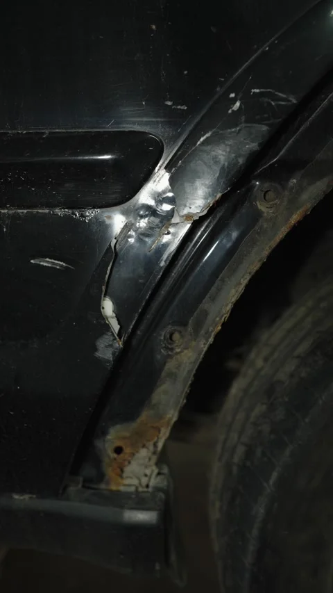 Scratched and chipped paint on a damaged black car wheel arch Stock Footage 340336384