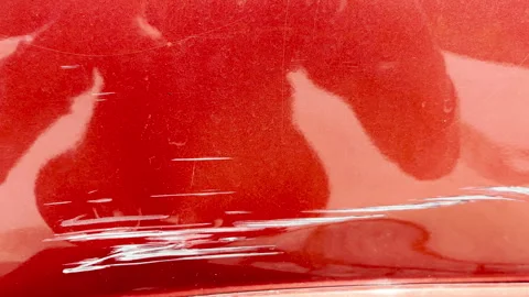 Scratches and reflection on red metallic car surface with visible swirl marks Stock Footage 310191497
