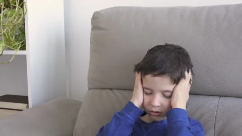 Scratching head sitting on a sofa Vidéo 253636560