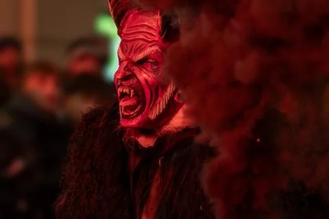 A screaming krampus in a red light during a night festival. Stock Photos