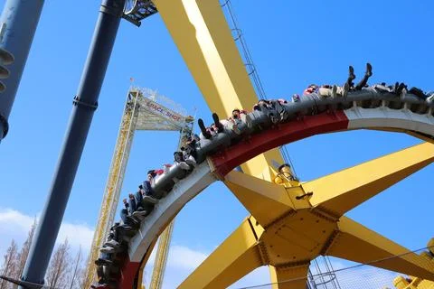 Screaming passengers on a high-speed looping coaster ride on a sunny day Stock Photos