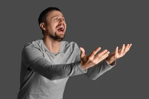 Screaming young man on dark background Stock Photos