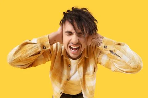 Screaming young man having panic attack on yellow background Stock Photos