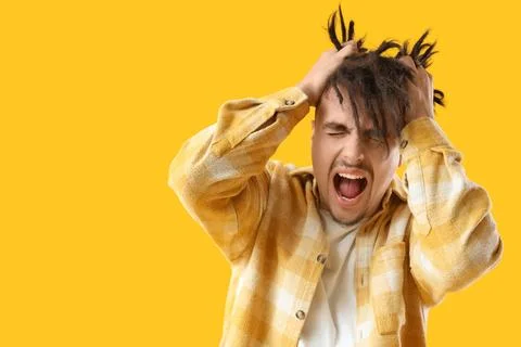 Screaming young man having panic attack on yellow background Stock Photos