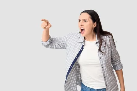Screaming young woman pointing at something on white background Stock Photos