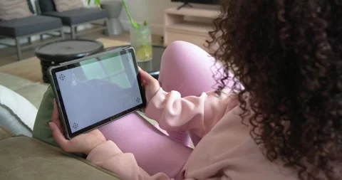 Screen glare is causing person to be tilting and repositioning tablet on couch Stock Footage 334999790