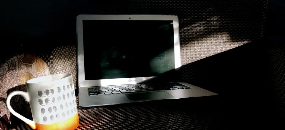 Screen of laptop kept on the couch with a steaming cup of coffee Foto stock
